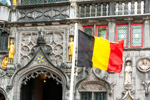 Basilica of the Holy Blood on burg square, with belgian flag in Brugge. Belgium. May 27, 2022.