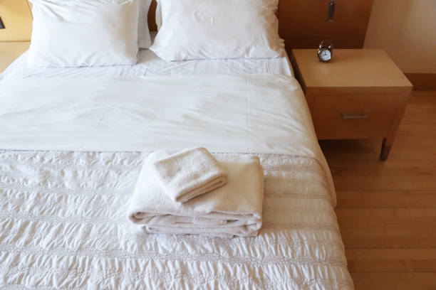 A messy white bed in a room at early morning