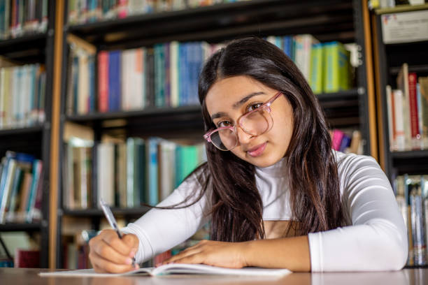 istock Girl doing homework in the library 1464149643