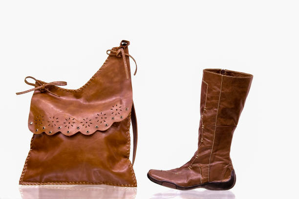 Brown leather women's boots with a handbag on a white isolated background.