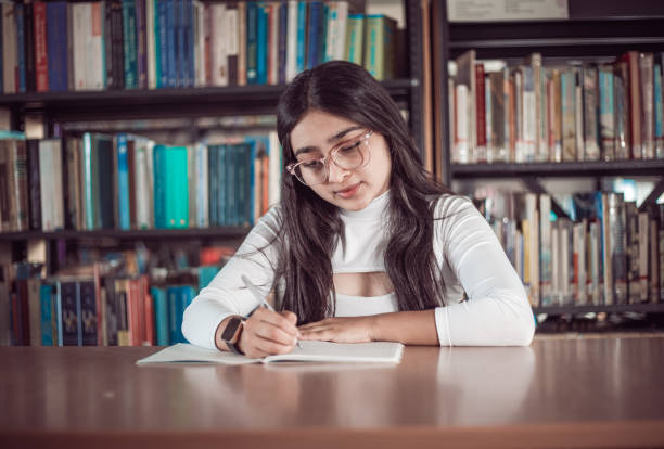 istock Girl doing homework in the library 1464150202