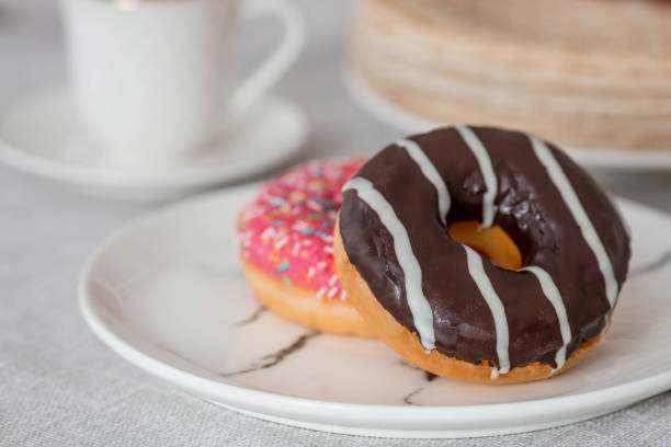 delicious dessert. pink and chocolate donut, with multicolored sprinkles, a cup of black coffee or tea. sweets. - baked bread breakfast brown imagens e fotografias de stock