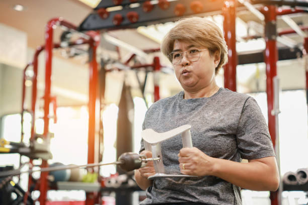 middle aged woman exercising Use a pull-up machine in the gym. stock photo