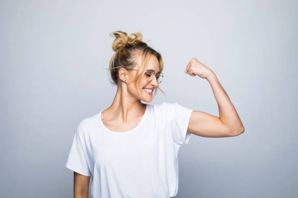 feliz mujer hermosa flexionando músculo - flexing muscles fotografías e imágenes de stock