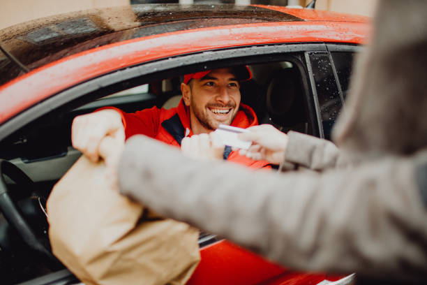 istock Smiling delivery man taking a credit card from a customer while delivering an order 1464159752