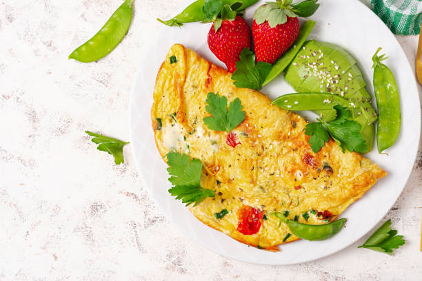 Omelette with tomatoes, feta cheese and avocado on white plate. Top view, flat lay stock photo