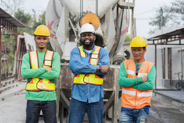 istock Portrait of foreman builder and workers standing together at construction site. Group of diverse construction site workers or controller standing behind cement truck at construction work 1464165209