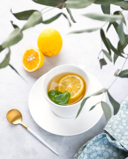 istock Herbal tea with lemon and mint in a white cup on a light background with eucalyptus branches. The concept of a healthy and delicious breakfast drink for immunity. 1464167263