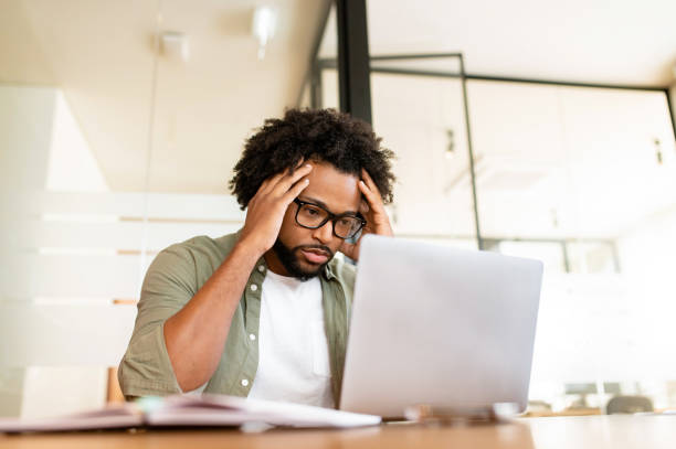istock Focused on solving tasks african-american freelance guy staring at laptop screen sitting in the office 1464167271