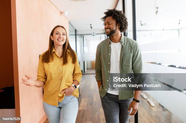 Couple Of Business People Discussing Tasks Walking In The Office Hall Stock Photo - Download Image Now