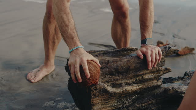 Man trying to break a coconut at the beach