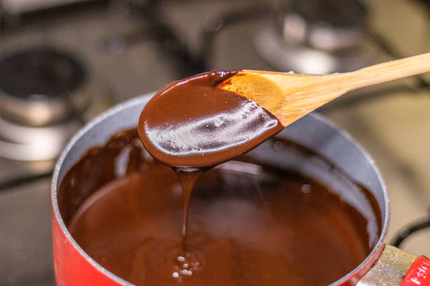 istock Wooden spoon stirring melting dark chocolate over a red pan 1464170892