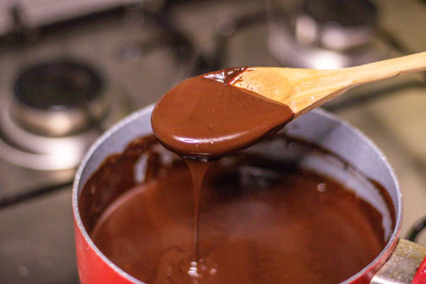 istock Wooden spoon stirring melting dark chocolate over a red pan 1464170901