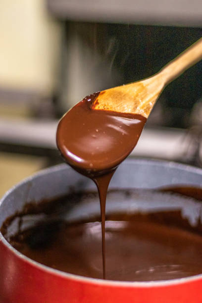 istock Wooden spoon stirring melting dark chocolate over a red pan 1464170938