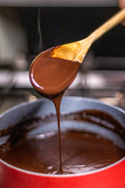istock Wooden spoon stirring melting dark chocolate over a red pan 1464170956