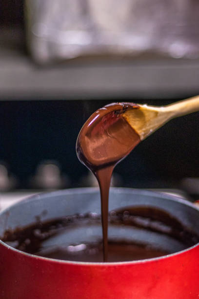 istock Wooden spoon stirring melting dark chocolate over a red pan 1464170977