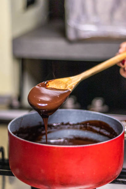 istock Wooden spoon stirring melting dark chocolate over a red pan 1464170978