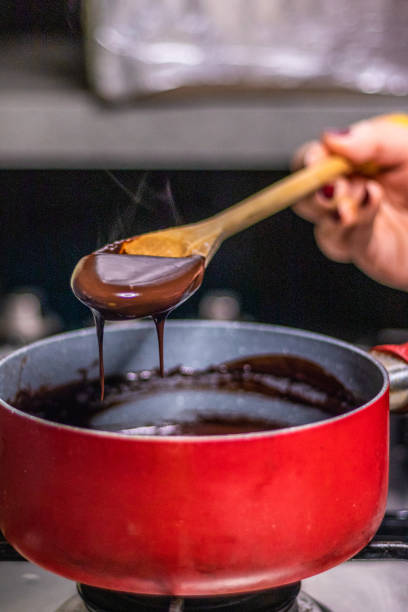 istock Wooden spoon stirring melting dark chocolate over a red pan 1464170980