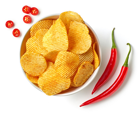 Bowl of crispy wavy potato chips or crisps with chili pepper flavor isolated on white background, top view