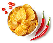 Bowl of crispy wavy potato chips or crisps with chili pepper flavor