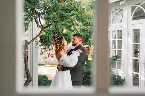 view through the window of a loving and beautiful couple of newlyweds in the park. the concept of organizing a wedding and romance.