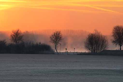 Bright orange sunrise over river IJssel on a cold morning