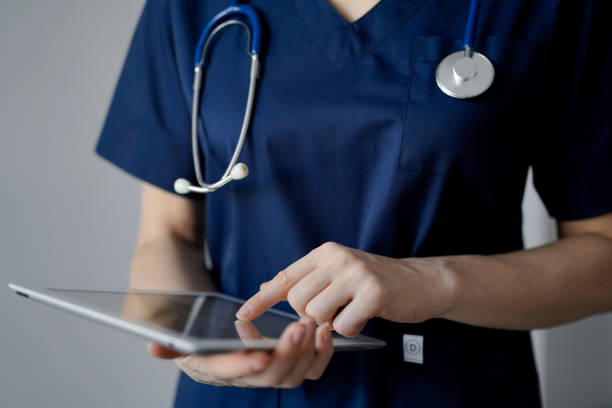 istock Doctor woman using tablet computer while standing near panorama window in clinic, close up. Physician or surgeon at work. Medicine concept 1464186514