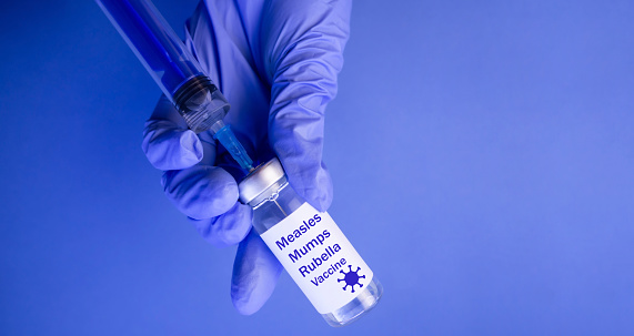 Vaccine against measles, mumps, rubella on a blue background.Viral vaccine bottle. Medicine concept.