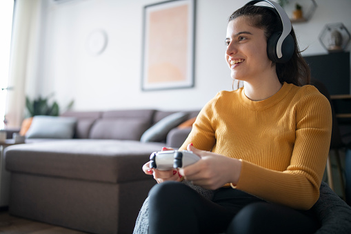 Young woman at home having fun playing video games.