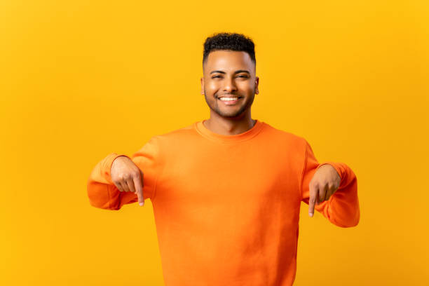 istock Look, advertise below. Cheerful indian guy pointing down place for commercial idea, looking at camera 1464190141