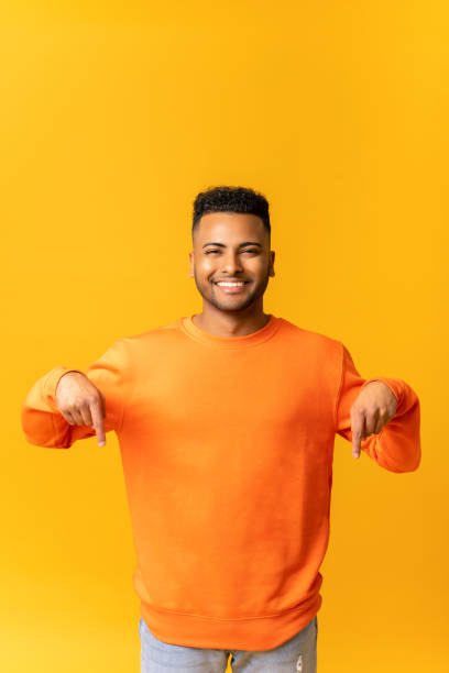 istock Attractive indian man with overjoyed facial expression pointing down with both fingers 1464190236