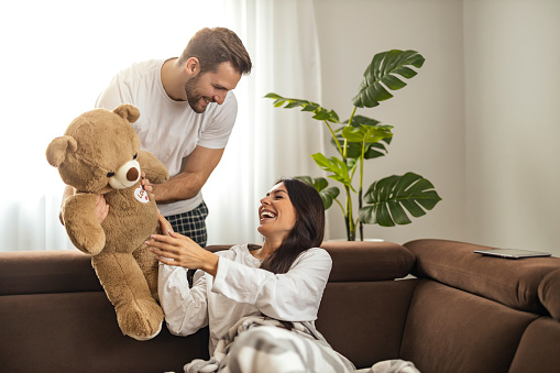 Young man giving teddy bear as present to his girlfriend.Romantic moments.