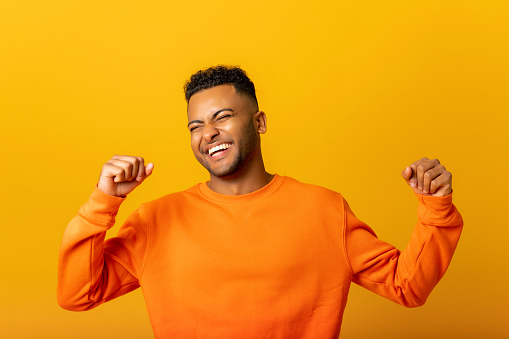 Extremely excited overjoyed indian man shouting making yes gesture, amazed with his victory, triumph. Indoor studio shot isolated on yellow background