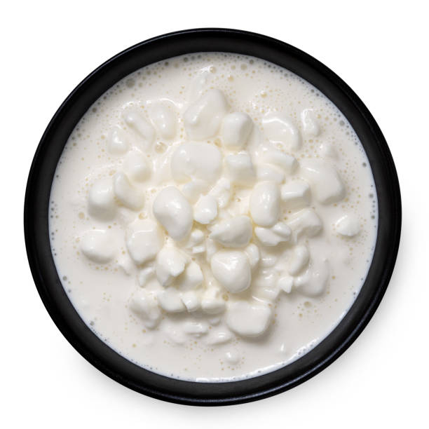 istock Chunky cottage cheese with whey in a black ceramic bowl isolated on white from above. 1464195392