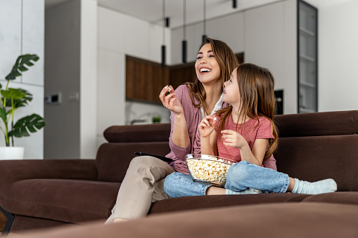 Happy young mom and her daughter watching cartoons on television.Happy moments together.