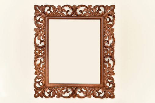 Vintage brown carved wooden frame for mirror hanging on the pale orange wall