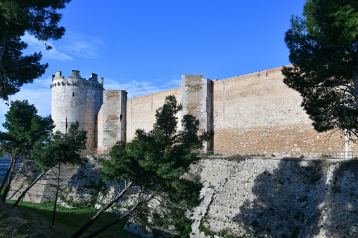 Lucera, Italy, 02/04/2023. View of the outer walls of an imposing medieval castle. It is located in Puglia in the province of Foggia.