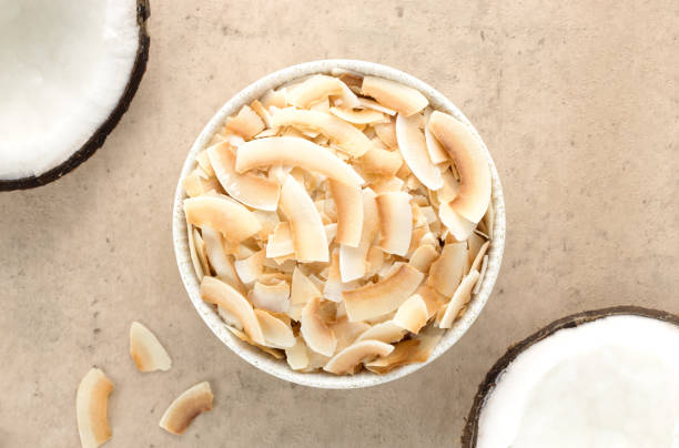 istock Coconut chips or coconut flakes with fresh half coconuts on a beige background. Top view.. Healthy snacks. Coconut dessert. 1464201302