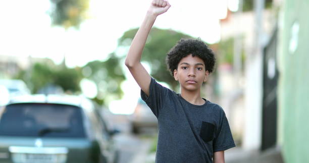 Mixed race kid raising fist in the air political protest stock photo
