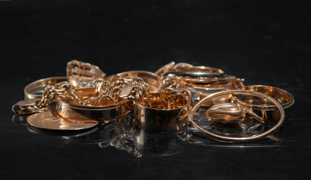 un mucchio di diversi gioielli d'oro su uno sfondo nero a specchio. - gold jewelry coin scrap metal foto e immagini stock