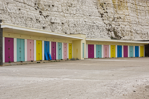 Multicoloured beach huts by white chalk cliffs at Saltdean near Brighton in East Sussex, England