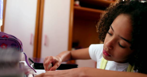 istock Little girl studying at home, mixed race child writing notes doing homework 1464206469