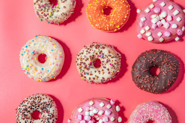 istock Donuts with icing on pastel pink background. Sweet donuts. top view assorted with various chocolate glazed and sprinkles, sugar sweets concept 1464208401