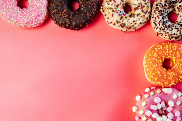 istock Donuts with icing on pastel pink background. Sweet donuts. top view assorted with various chocolate glazed and sprinkles, sugar sweets concept 1464208446