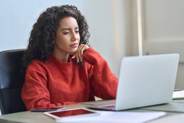 istock Young latin business woman working on laptop thinking analyzing online data. 1464209132