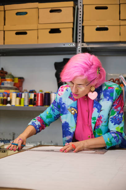 istock Seamstress with pink hair and colorfull clothes drawing sewing patterns. 1464209691