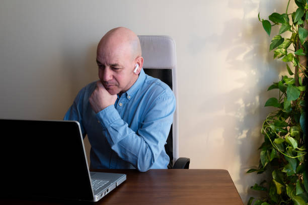 Handsome mid adult businessman sitting on a terrace, working on laptop computer and smoking a cigar.