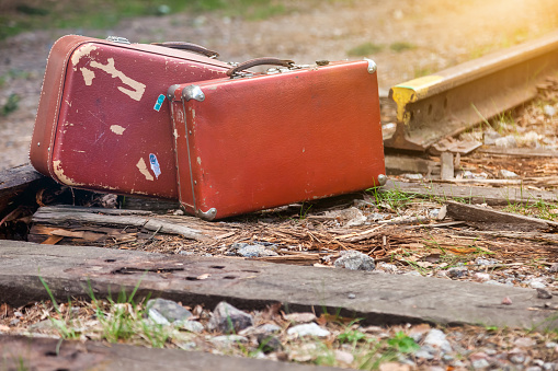 Two vintage suitcases standing on closed old railway rails outdoors. Stylish image forgotten retro suitcases in forest at railroad background. Travel vacation concept. Copy text space for advertising