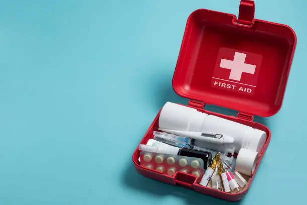 Photo of Home first aid kit on a blue background. The elements of the first aid kit