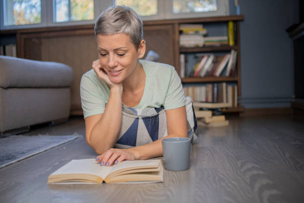 istock Happy woman reading book at home 1464217390